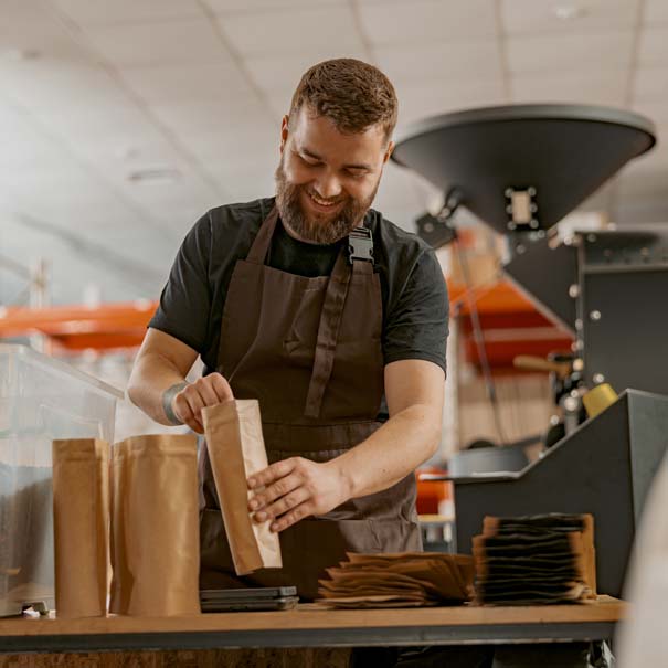 Business owner weighing a paper bag of coffee beans behind the counter