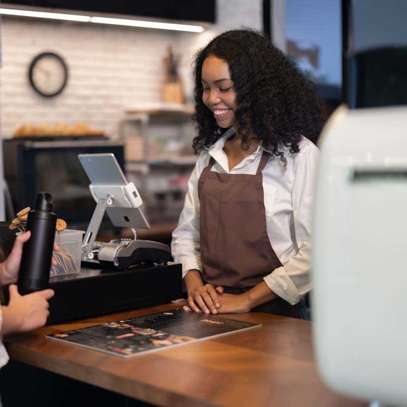 Shop owner handing a reusable bag to a customer at the counter